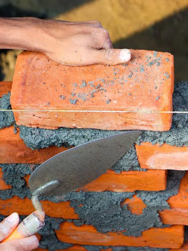 Pedreiro construindo parede de tijolos